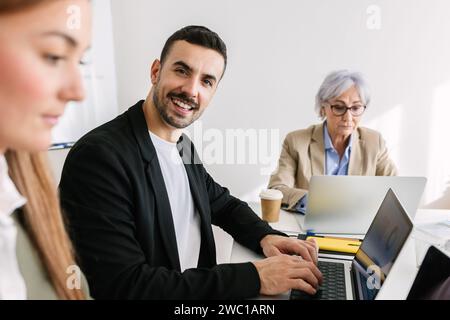 Smiling confident businessman looking at camera sitting with colleague friends. Stock Photo