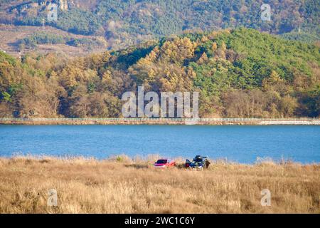 Sangju City, South Korea - November 18th, 2023: Cars are parked along the picturesque banks of the Nakdong River, offering a view of the river and the Stock Photo