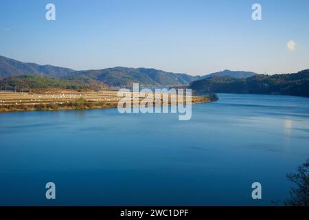 Sangju City, South Korea - November 18th, 2023: A sweeping view of the Nakdong River's horseshoe bend, flanked by farm fields, with cliffs and rolling Stock Photo