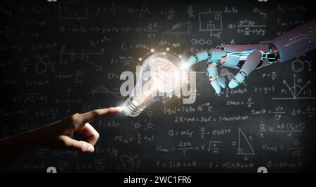Ai Robot hand and Human hand pointing a brain inside a light bulb on wall backboard or chalkboard background. Artificial Intelligence Business. Stock Photo
