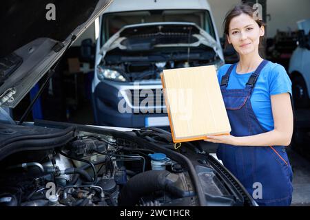 Woman stands with filter for car air conditioner near car Stock Photo