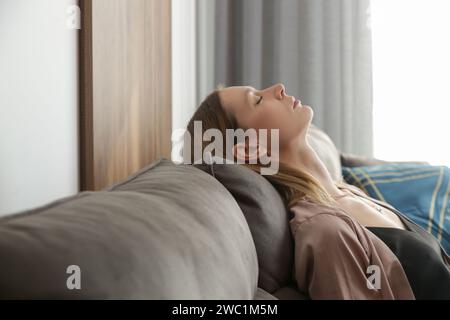 Side view of young pretty woman relaxing on the comfortable sofa. Stock Photo
