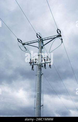medium voltage overhead line, pole with insulators and disconnectors, dark clouds in the background Stock Photo