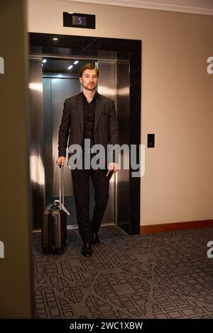 Serious young businessman walking out of hotel elevator Stock Photo