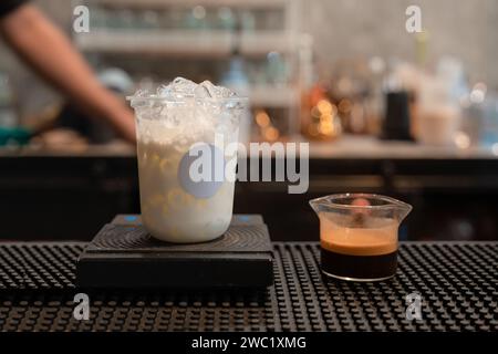 Glass of milk with ice and espresso shot for mixing as latte coffee on counter bar at coffee shop Stock Photo
