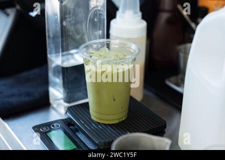 Iced green tea with ice cube in plastic glass on scale at cafe Stock Photo