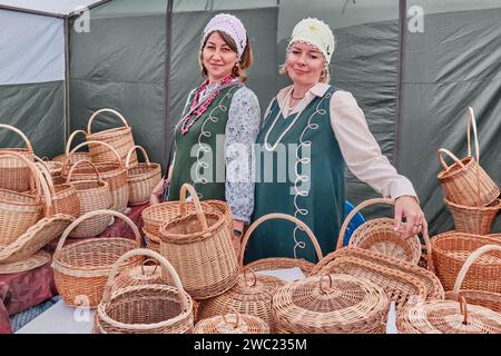 Caucasian women in stylized Russian outfits selling wicker baskets at Traditional Irbit fair, Russia Stock Photo