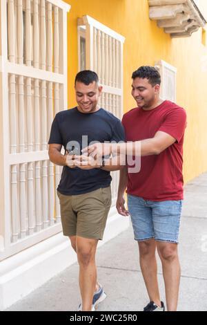 Latin men share a laugh while looking at a smartphone together. Stock Photo