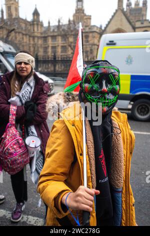 London, UK. 13th January 2024. Masked protestor.Pro-Palestine demonstration criticising the Israeli government and world leaders and calling for a ceasefire rallies in Parliament Square with the tailback going beyond Embankment tube. Manolo the Pomeranian wears his Palestinian colours with pride. Credit Peter Hogan/ALAMY Stock Photo