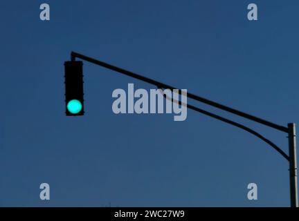 Traffic street light, up in the sky, showing green light. Go, keep moving, concept . Blue sky as background. Stock Photo