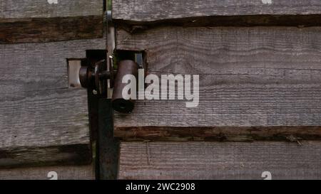 Hanging metal lock on a wooden gate. A dark metal castle in close-up in a gate made of wooden planks. Stock Photo
