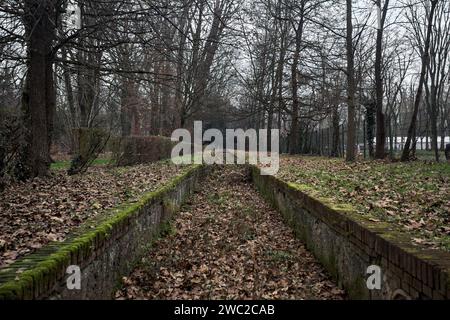 Ditch full of fallen leaves next to a wall in a park in autumn Stock Photo