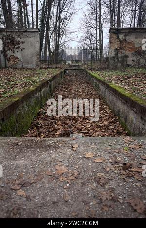 Ditch full of fallen leaves next to a wall in a park in autumn Stock Photo