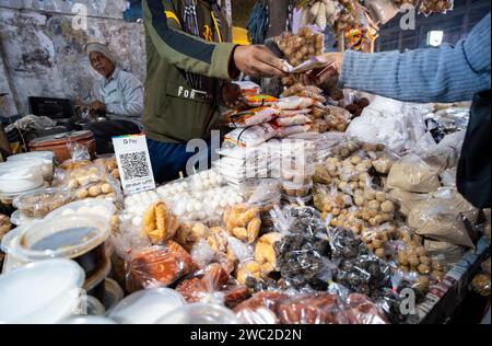 Vendor selling Assamese traditional food in a market, ahead of Magh Bihu Festival in Guwahati, Assam, India on 13 January 2024. Magh Bihu marks the end of the harvesting season, particularly the harvesting of paddy, and the beginning of the Assamese month of Magh. The festival usually falls in mid-January, and it is a time of joy and feasting. People express gratitude for the bountiful harvest and pray for prosperity in the coming seasons. Credit: David Talukdar/Alamy Live News Stock Photo