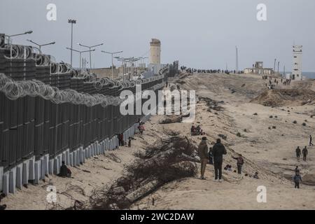 Rafah, Palestinian Territories. 13th Jan, 2024. Displaced Palestinians from northern Gaza walk near the wall separating Egypt and the Gaza Strip. Credit: Mohammed Talatene/dpa/Alamy Live News Stock Photo