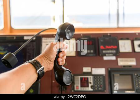 Navigational control panel and VHF radio with hand. Radio communication at sea. Working on the ship's bridge. Stock Photo