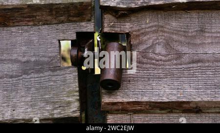 Hanging metal lock on a wooden gate. A dark metal castle in close-up in a gate made of wooden planks. Stock Photo