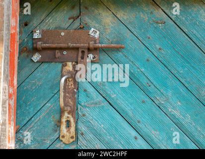 Metal rusty deadbolt and doorknob on old worn green door. Stock Photo