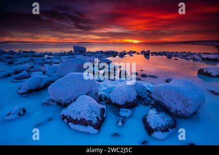 Winter sunset with snowy boulders and icy coastline at Teibern in Larkollen by the Oslofjord, Østfold, Norway, Scandinavia Stock Photo