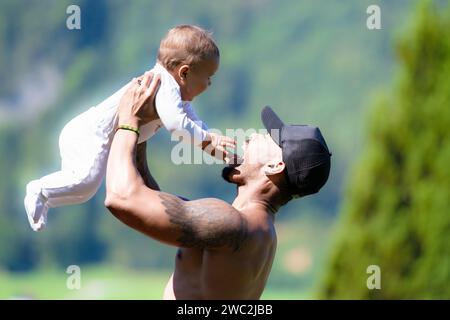 Close up portrait of afro american father kissing multiracial Biracial baby. Father hug Biracial child oudoor. Father with Biracial baby on nature Stock Photo