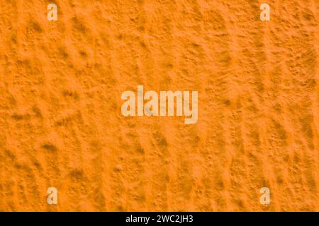 Uneven abstract texture of yellow paint. Abstract background of orange plaster. Stock Photo