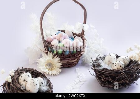 Chocolate eggs in a basket surrounded by dried flowers and bird's nests on lilac background Stock Photo