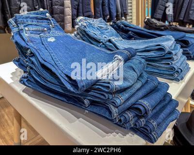 Blue jans folded and stacked on table displayed for sale in clothing store Stock Photo