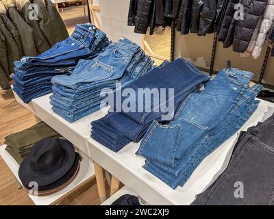 Blue jeans folded and stacked on table displayed for sale in clothing store Stock Photo