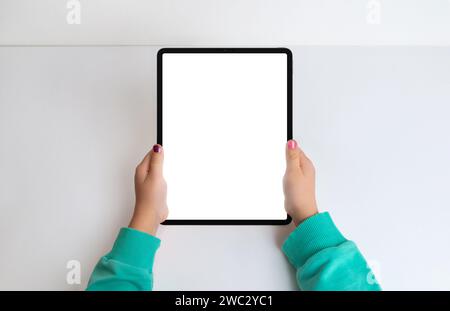 Girl's hands with tablet in a top view flat lay, featuring an isolated screen for mockup. Create a modern aesthetic for digital content and app presen Stock Photo