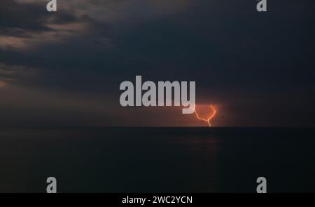 Lightning over the sea during a thunderstorm on a summer night Stock Photo