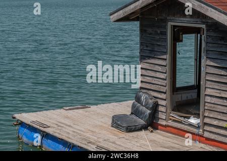 Old abandoned fishing shack and dock floating on surface of lake Stock Photo