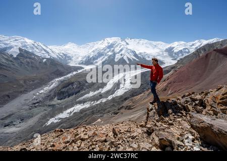Mountaineer points into the distance, at Traveller's Pass with view of impressive mountain landscape, high mountain landscape with glacier moraines Stock Photo