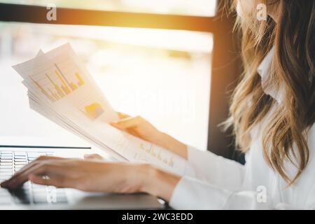 Businesswoman working and comparing forecasting and graphic documents paperwork with laptop Stock Photo