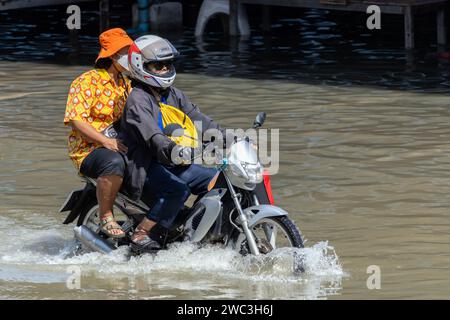 SAMUT PRAKAN, THAILAND, NOV 18 2023, A pair rides a motorcycle through a flooded street Stock Photo