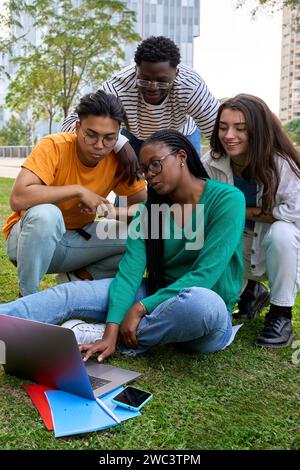 Group of young international university students sitting on the grass outside the faculty building Stock Photo