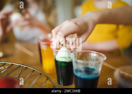 Using food coloring to dye Easter eggs at home. Painting colorful eggs for Easter hunt. Getting ready for Easter celebration. Family traditions. Stock Photo