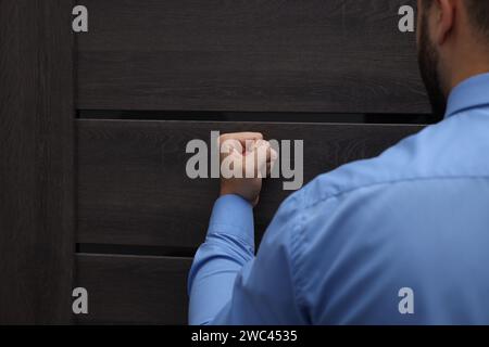 Collection agent knocking on wooden door, closeup Stock Photo