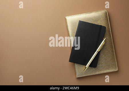 Different notebooks and pen on light brown background, top view. Space for text Stock Photo