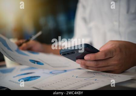 Businessman working with smartphone presentation analyzing data planning documents graphs and chart on desk Stock Photo