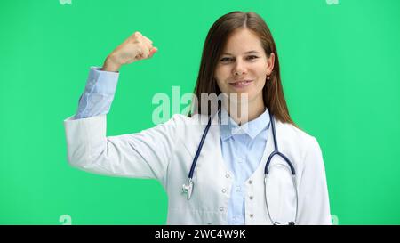 Female doctor, close-up, on a green background, shows strength Stock Photo