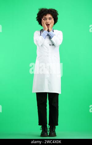 A female doctor, full-length, on a green background, is surprised Stock Photo