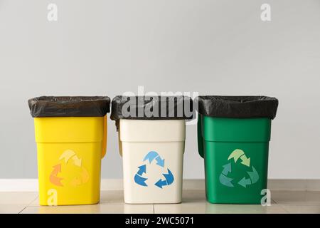 Empty trash bins with recycle logo near grey wall Stock Photo