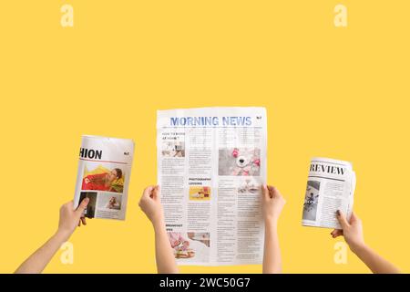 Women with newspapers on yellow background Stock Photo