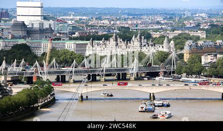 London, UK - 10th October 2023: Aerial shot of boats on River Thames and red double decker buses on Waterloo Bridge. Hungerford and Golden jubilee bri Stock Photo