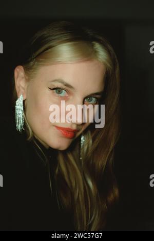 An attractive young woman with captivating eyes adorned in elegant silver earrings and dressed in a stylish black sweater Stock Photo