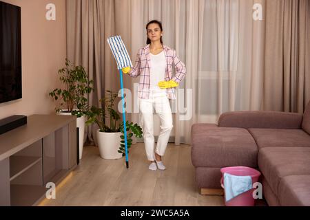 young woman cleaning and mopping floor at living room at the evening, daily housekeeping Stock Photo