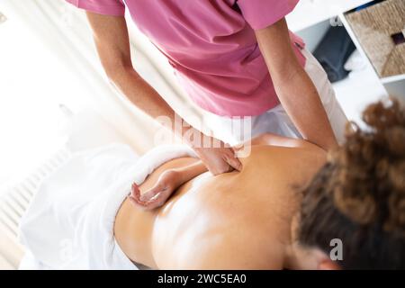 Professional osteopath using fist while massaging back of client Stock Photo