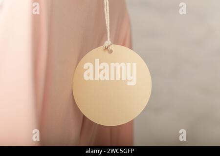 Close up of price tag of clothing item. Blank round label tag mockup on a clothes. Fashion industry and retail concept. Stock Photo