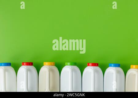 White plastic bottles with differently colored caps on a beautiful green background, environmental concept, copy space Stock Photo