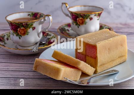 Battenberg cake and China cups with tea Stock Photo